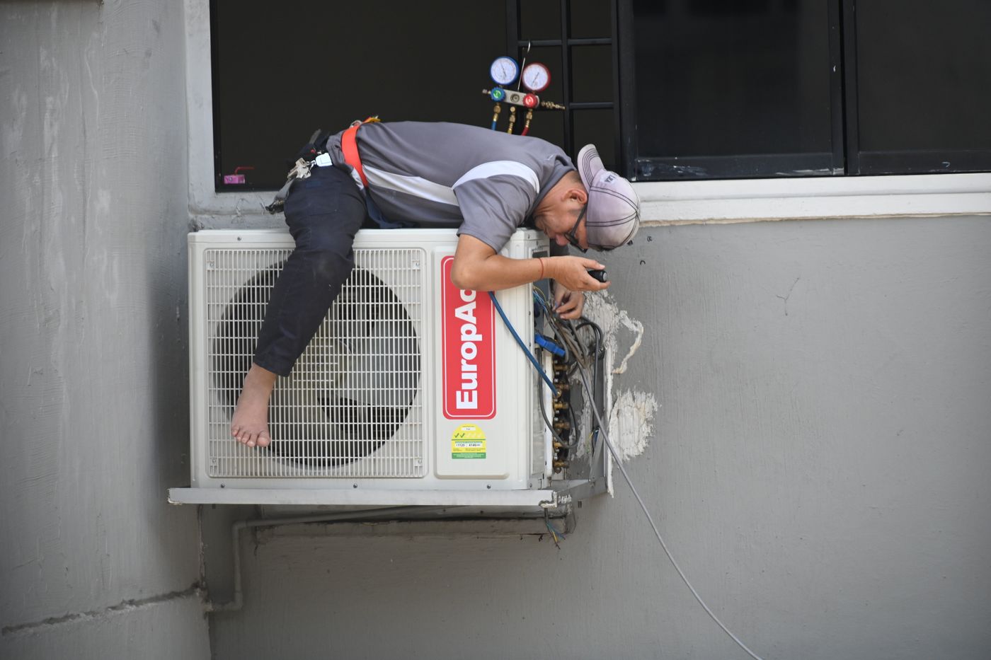 Engineer fitting an outdoor condenser unit to an exterior wall